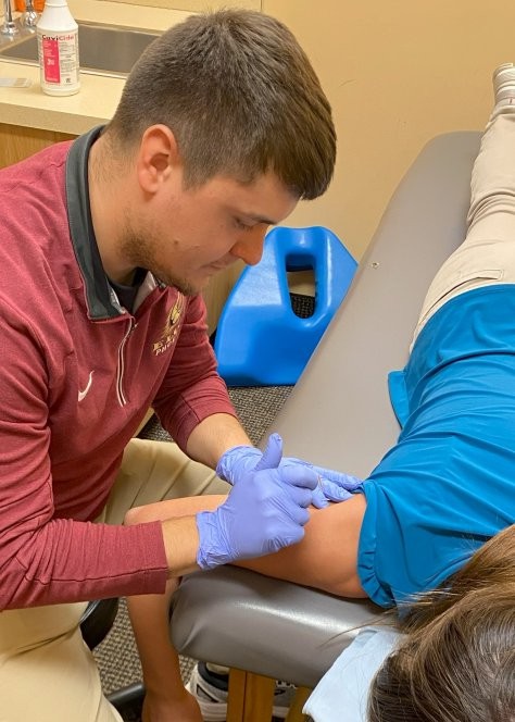 A physical therapist works on a patient's shoulder