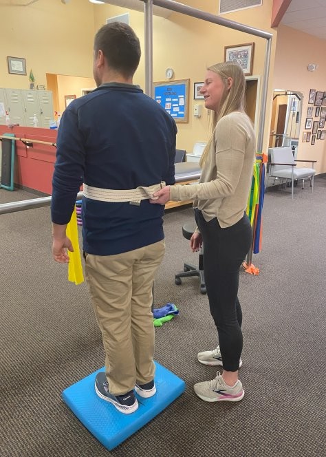 A physical therpaist helps a patient with balance